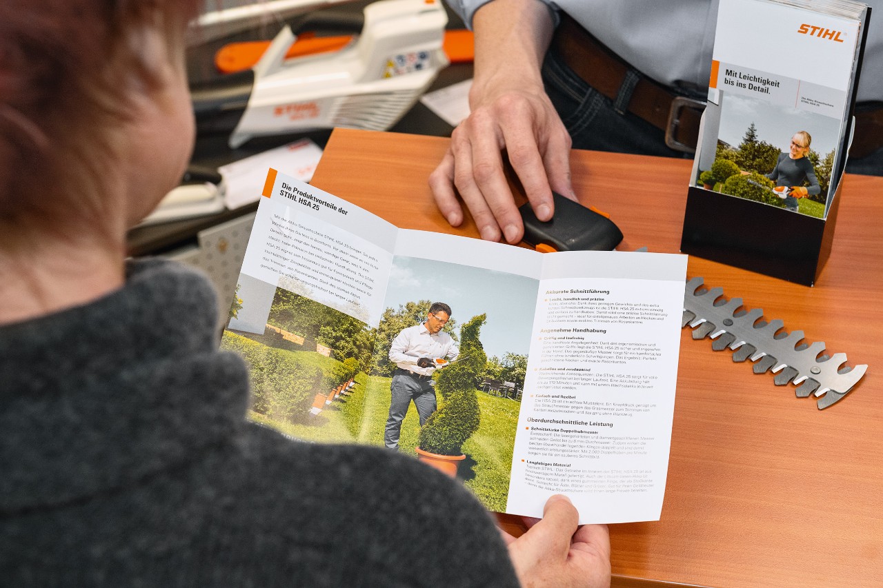 Лице кое чита за придобивките од производот STIHL HSA 25 во брошура