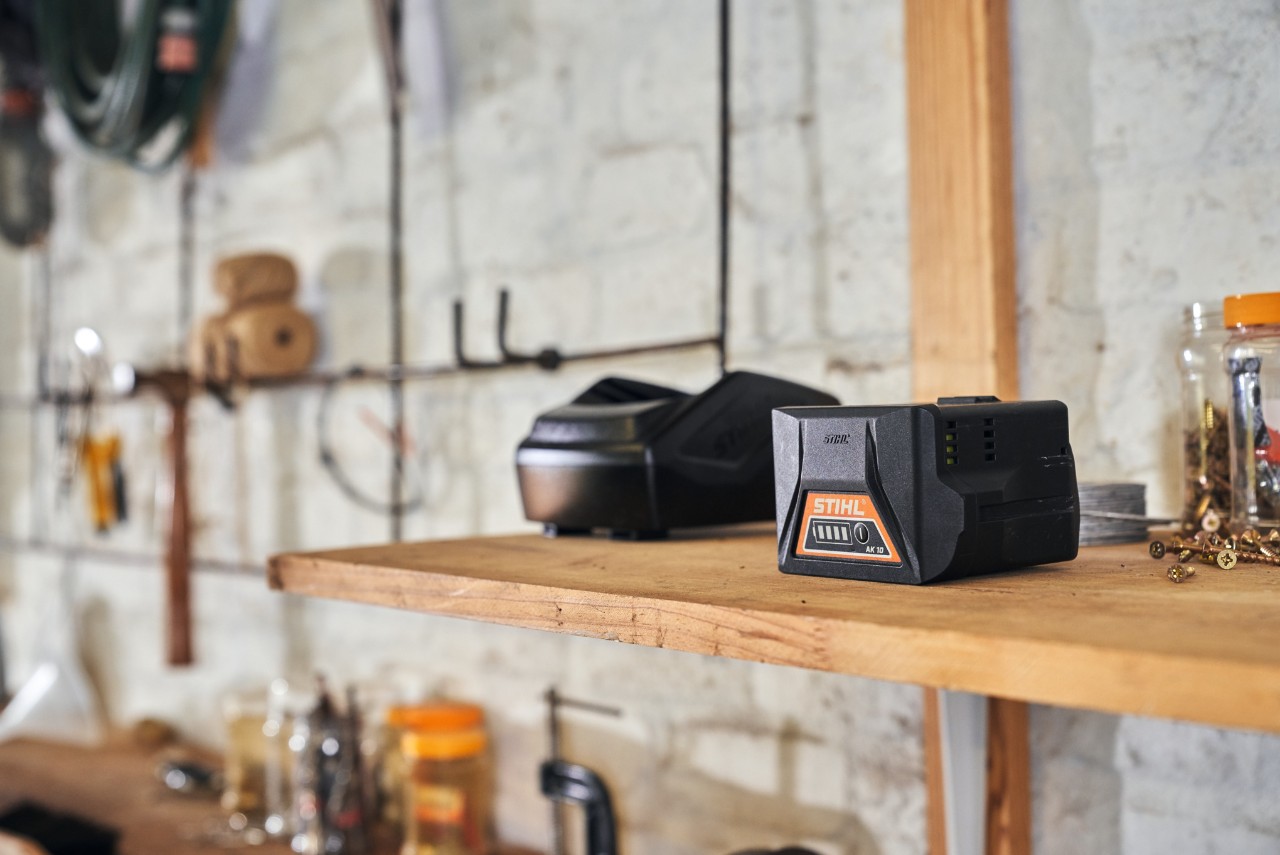 Две батерии со STIHL технологија на батерии лежат на полица во работилница