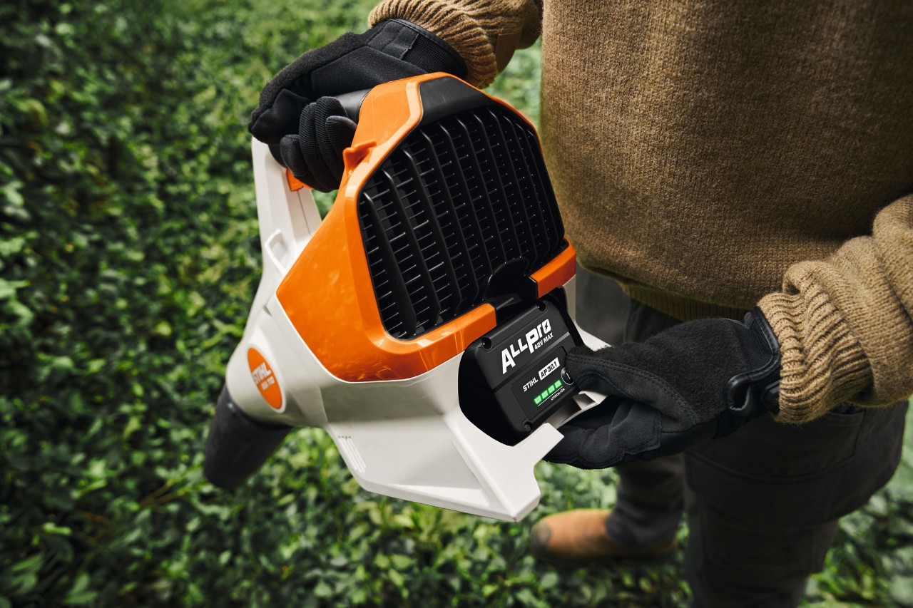 Човек го вклучува својот безжичен дувач за лисја STIHL BGA 110 со батеријата STIHL AP 30 Evo 1 ALLPRO.