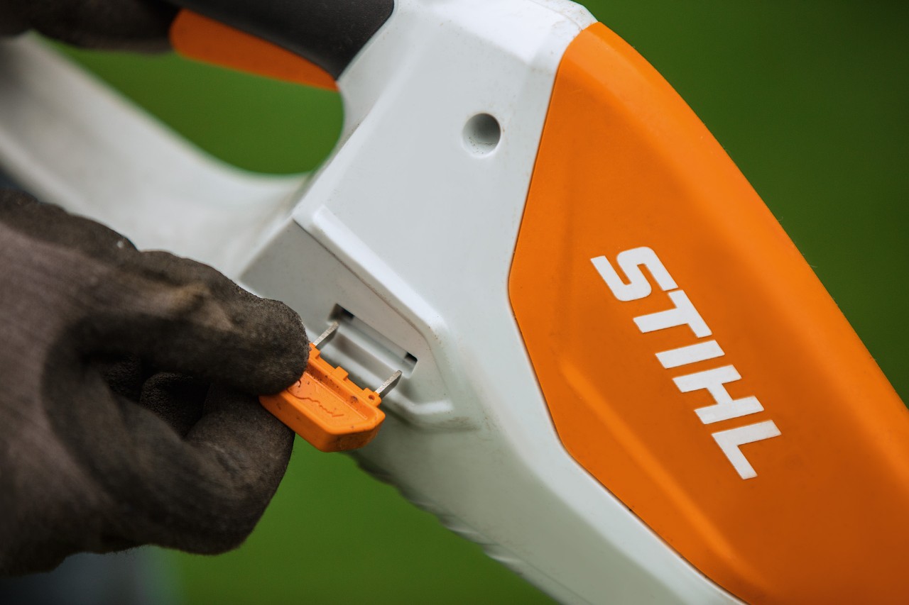 Крупен план на клучот за активирање на безжична тример за трева STIHL со вградена батерија