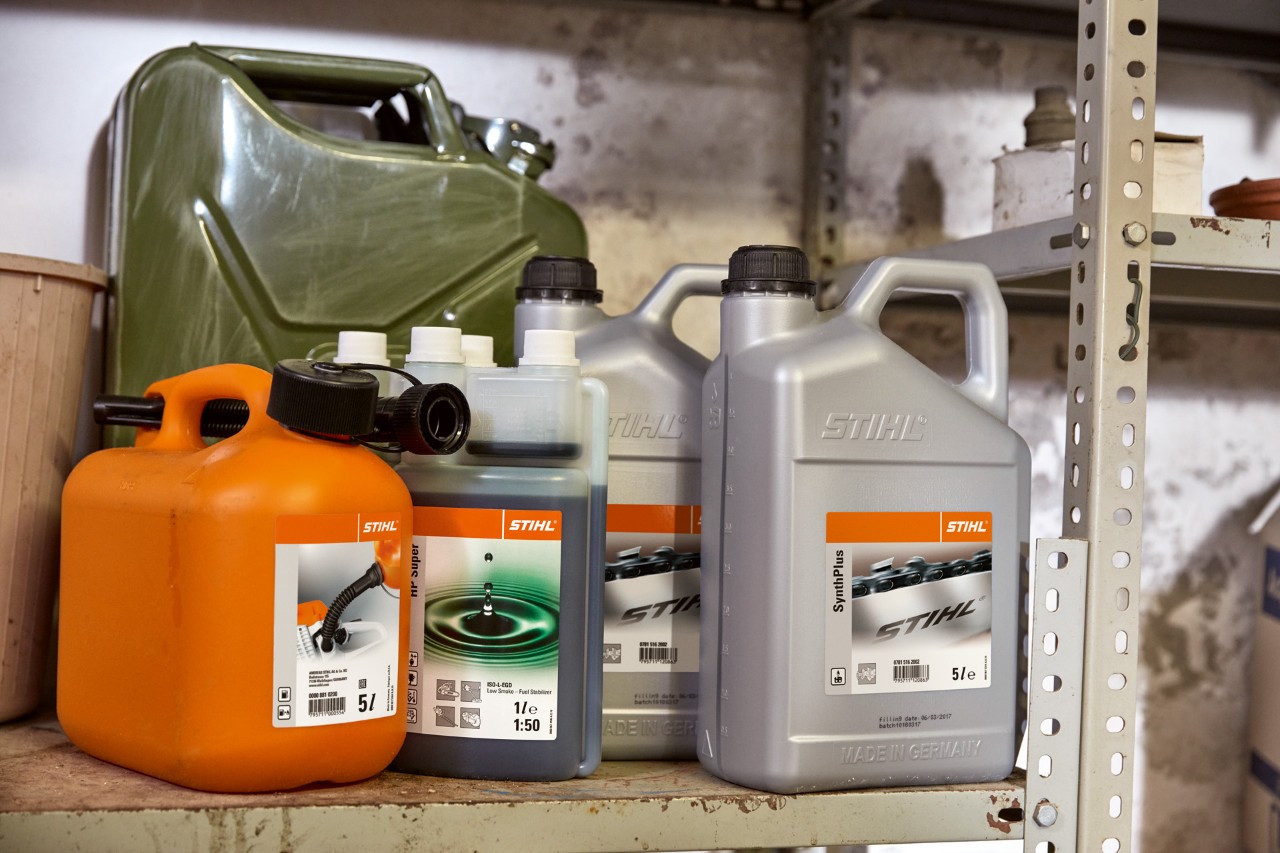 Колекција канистри, вклучувајќи шише масло за двотактен мотор STIHL HP Super и портокалов комбиниран канистер