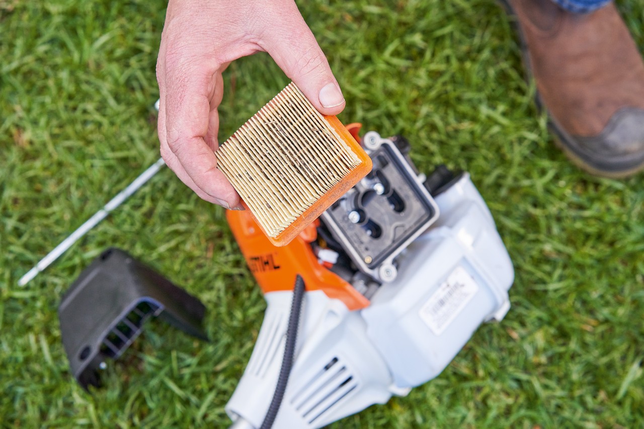 Лице кое го вади филтерот за воздух од косата за грмушки STIHL за да го исчисти 