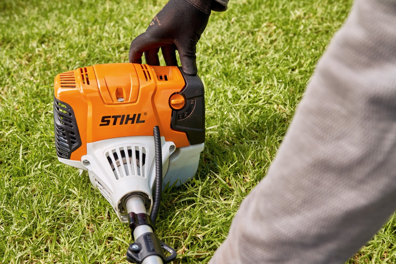 Човек цврсто притиска бензинска коса STIHL FS 91 на земја