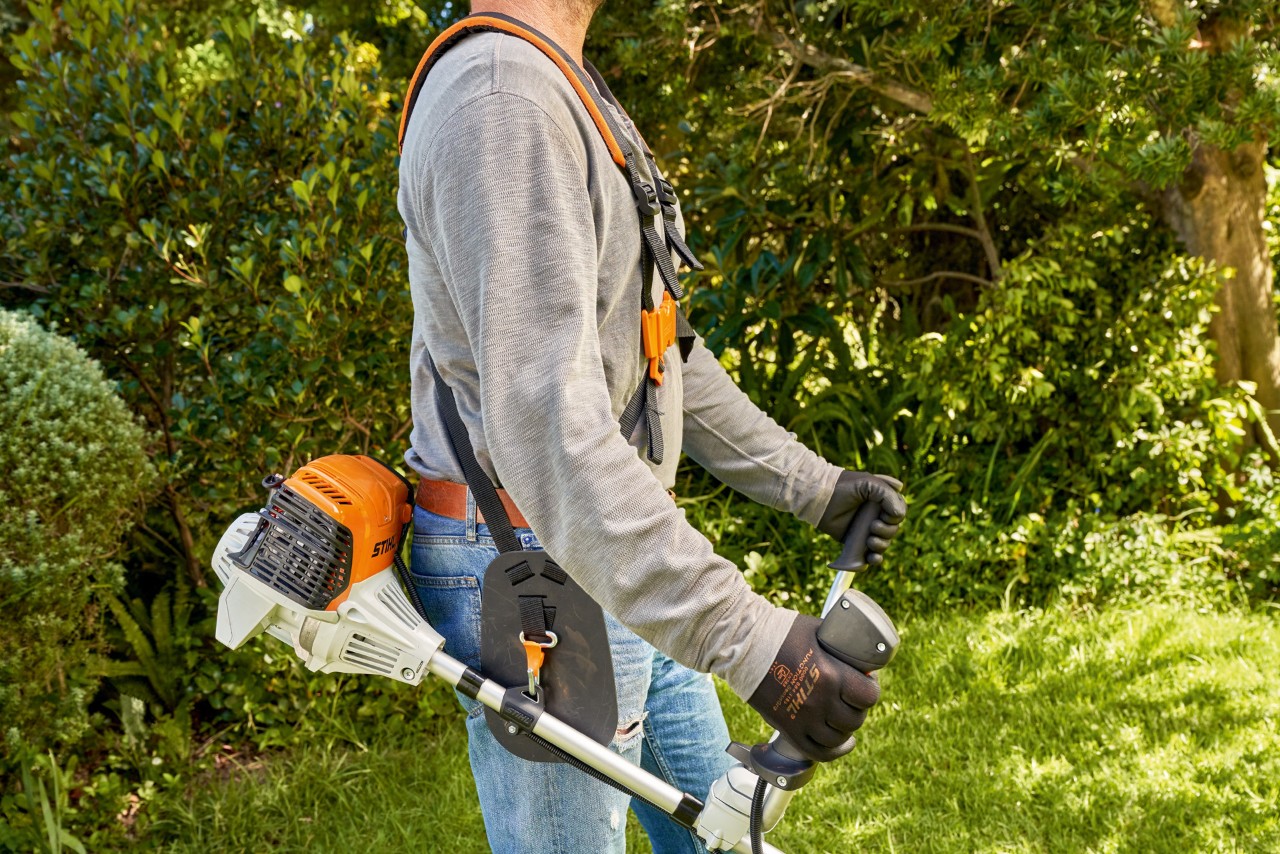 Човек крева бензинска коса STIHL FS 91 од земја за да почне да коси 