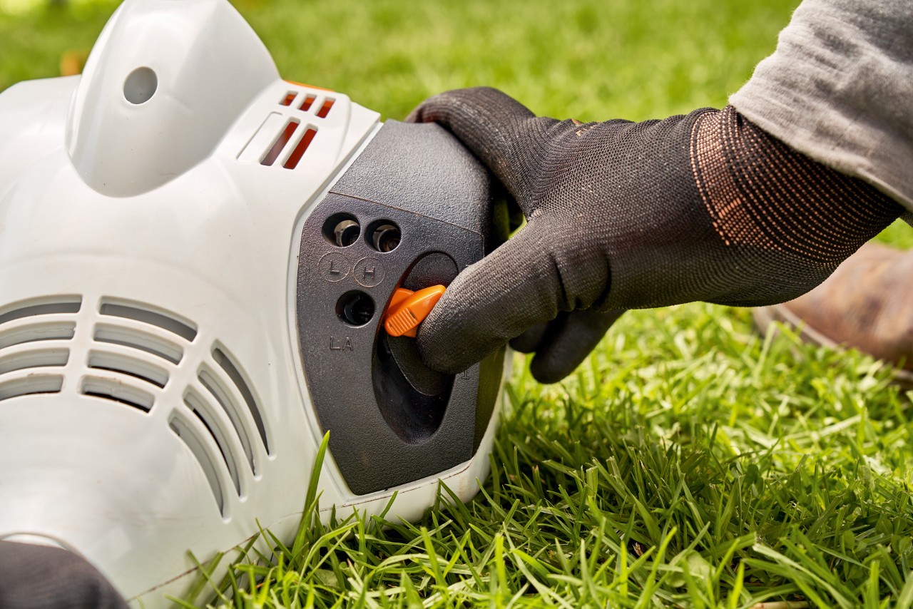 Човек ја прилагодува рачката на бензинскиот тример  STIHL FS 56 за да го запали