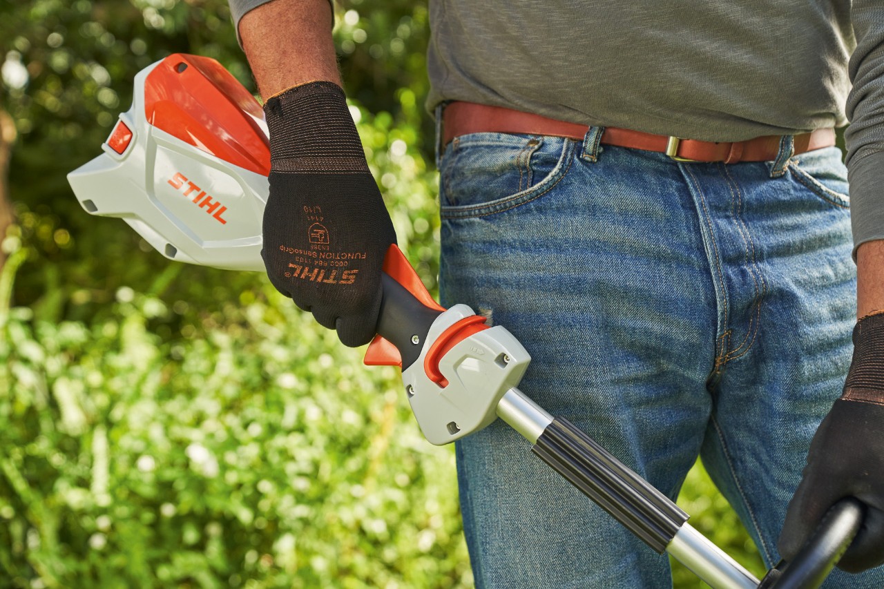 Човек со заштитни ракавици го отпушта прекинувачот на батериската коса STIHL FSA 60 за да ја исклучи.
